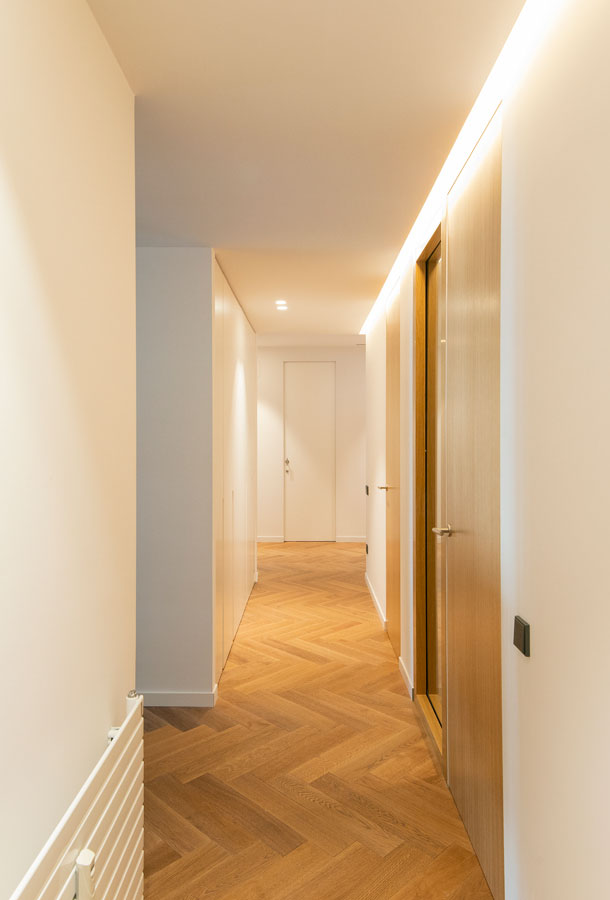 Pasillo con parquet de espiga y puertas en madera| The Room Co